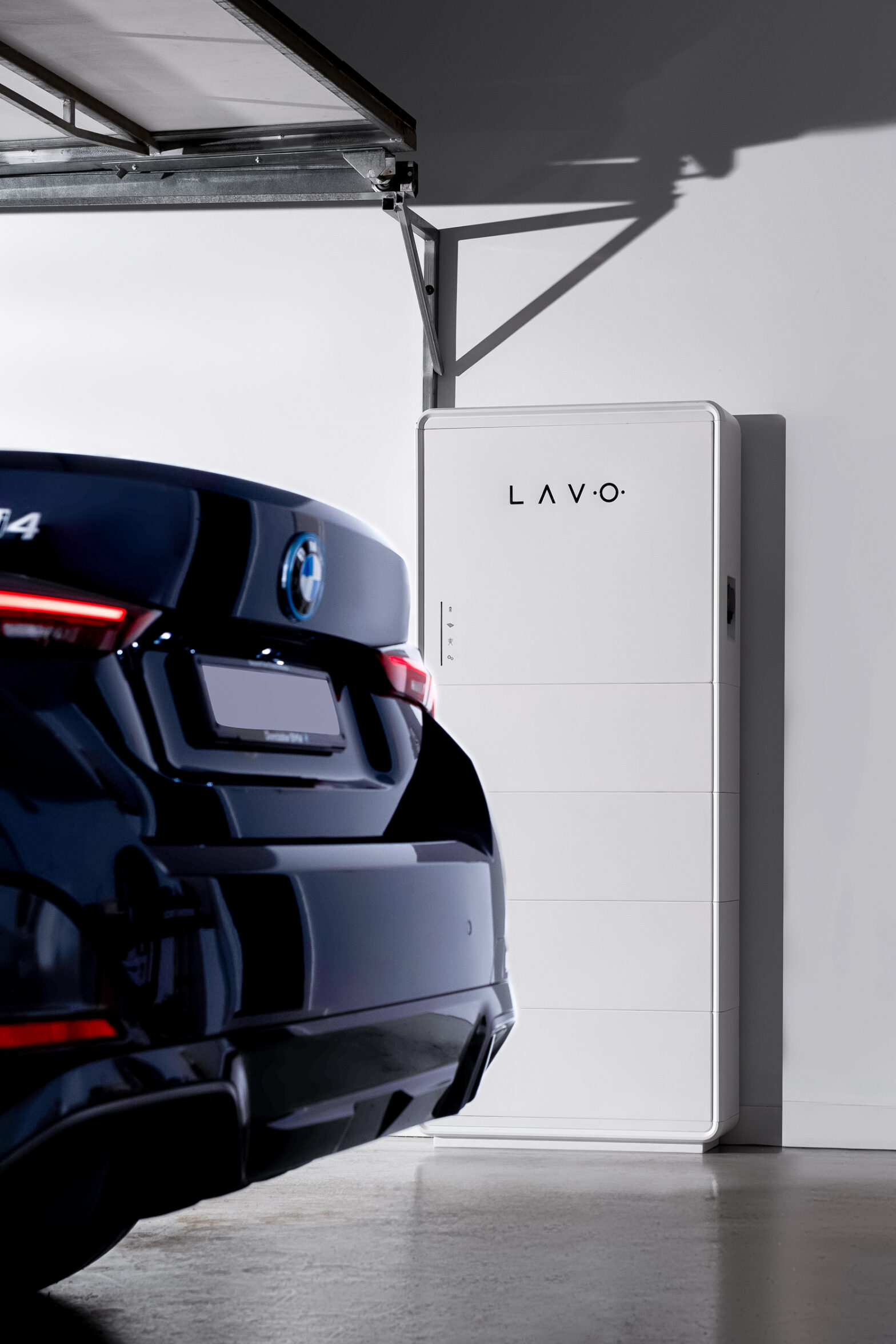 A black car is parked in a garage next to a white energy storage unit labeled "Lavo".